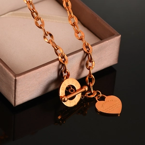 Dettaglio macro del ciondolo a cuore in oro rosa e chiusura a T con testo inciso sopra