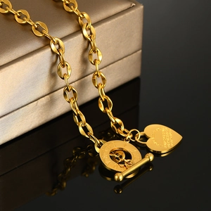 Dettaglio macro della collana OT dorata con ciondolo a cuore e incisione