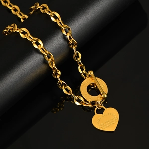 Dettaglio della collana OT dorata con ciondolo a cuore e proverbi incisi