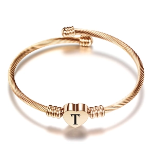Detail van roségouden gedraaide kabelarmband met een gegraveerd hart en de letter T