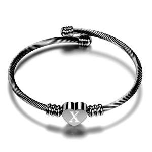 Detail van hartbedeltje met letter X op zwart en zilver gevlochten kabelarmband