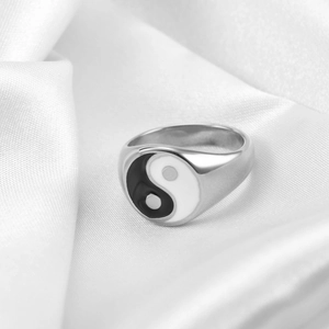 Detailed macro shot of Yin Yang enamel signet ring on white silk background texture