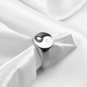 Macro shot of Yin Yang signet ring on white silk, showing polished silver finish and enamel detail
