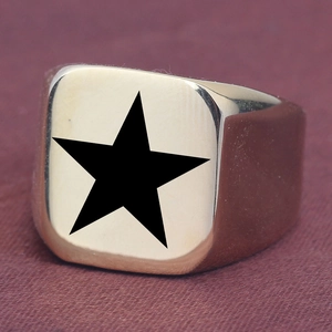 Detail of gold signet ring featuring square face and black pentagram star engraving