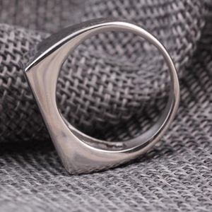 Bague bouclier géométrique en argent poli au design minimaliste sur fond texturé