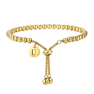 Detailopname van een gouden kralenarmband met gegraveerde letter U-hanger en verstelbare sluiting