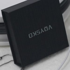 Close-up of black textured jewelry box with silver logo and subtle metal chain detail