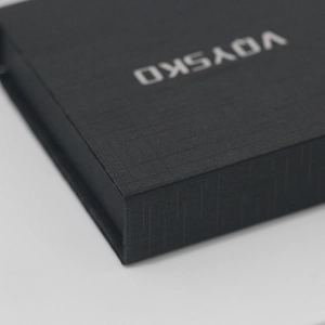 Macro shot of black jewelry box with cross texture and silver logo detail