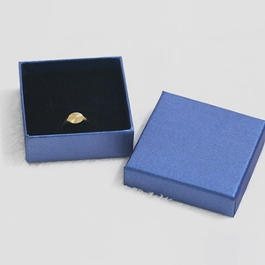Golden ring with radial sunburst pattern set against a blue textured jewelry box