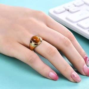 Gros plan d'une large bague en acier inoxydable doré 18K avec œil de tigre sur la main