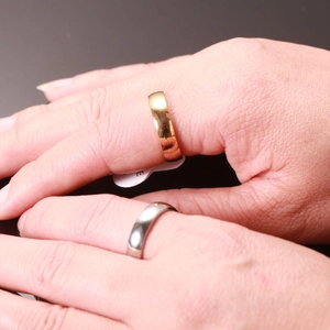 Anillos de banda de acero inoxidable pulido en oro y plata mostrados en los dedos