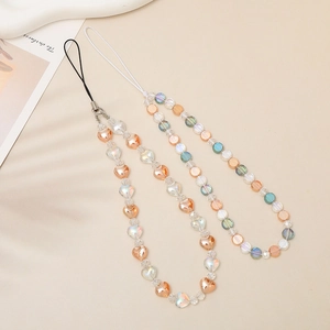 Detail of peach heart and iridescent round crystal beaded phone straps on soft beige background