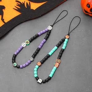 Close-up of beaded Halloween phone charms with pumpkins and skulls on dark textured surface