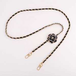 Detail of camellia flower charm with pearls on a black leather and gold chain strap