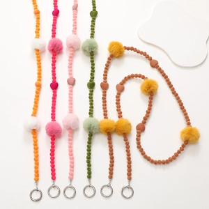 Detail of colorful plush pompom phone charms with heart beads and metal clasps