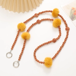Detailed view of plush mobile phone strap with brown beads and yellow fur pom poms