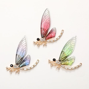 Dettaglio macro di ciondoli a libellula colorati con ali glitterate e strass luccicanti