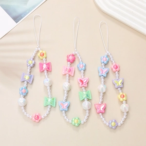 Détail de lanières de téléphone perlées avec breloques papillon, fleur et bonbon
