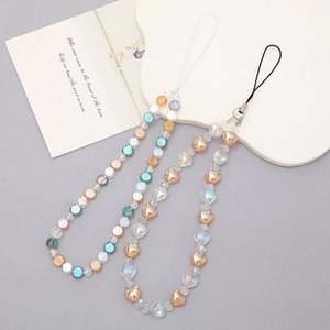 Detail of beaded phone charms with heart-shaped beads and metallic accents on display