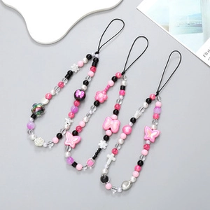 Detailed view of four colorful beaded phone charms with butterfly and floral ornaments