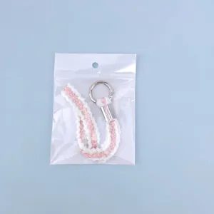 Pink and white woven keychain wrist strap with silver metal ring in clear packaging