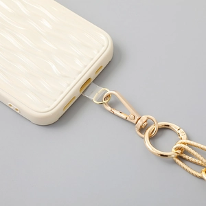Detail view of wavy cream phone case with gold chain strap and clear connector tab