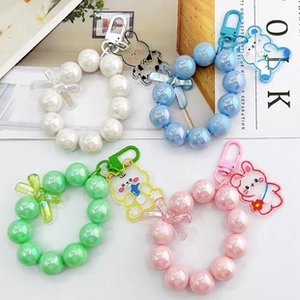 Detail of colorful pearl bead keychains with acrylic cartoon charms and bows