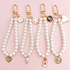 Detail of luxury pearl keychain with camellia, golden number 5, and heart pendants