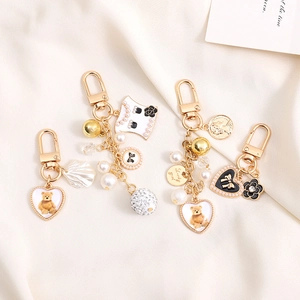 Porte-clés doré élégant avec charms nœuds en perles et accents de camélia sur tricot