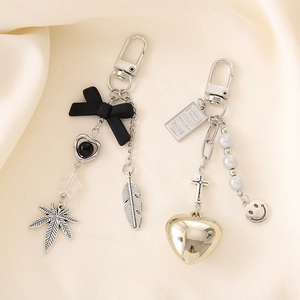Creative cross keychain pendant with black bow and golden heart charm on satin fabric