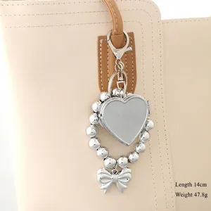 Silver heart and bow beaded charm pendant on beige bag, 14cm length and 47.8g weight