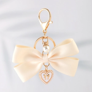 Sweet cream satin ribbon bow keychain with a golden heart pendant and pearl detail