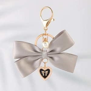 Macro detail of elegant grey ribbon bow keychain with a pearl and heart charm