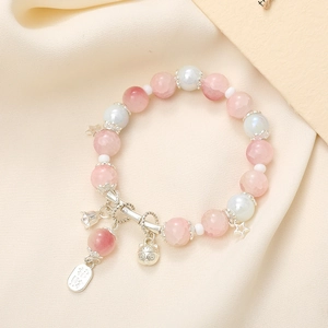 Close-up of pink and white beaded bracelet with Lucky Cat and bell charms on silk