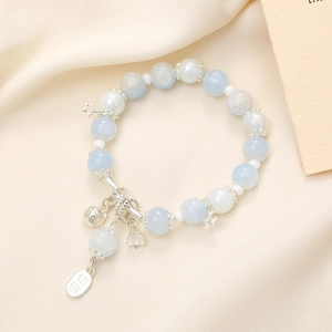 Close-up of beaded bracelet with blue moonstones and silver lucky charms on silk