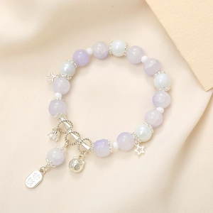 Close-up of beaded crystal bracelet with silver cat, star and bell lucky charms