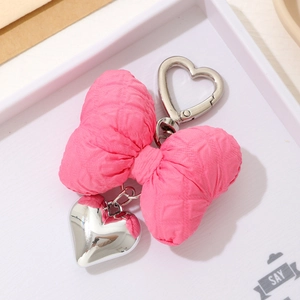 Close-up of pink fabric bow keychain with silver heart pendant and metal spring clasp