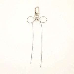 Detailed close-up of a silver snake chain metal bow pendant with a lobster clasp
