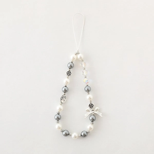 Détail de la lanière de téléphone avec breloques camélia, perles et pendentifs argent