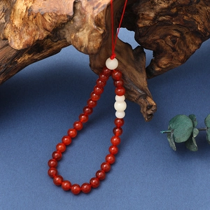 Detail of red agate beads and white jade accents on a retro Chinese phone charm strap