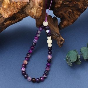 Detailed close-up of purple agate beads on a handmade phone strap with white accents