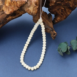 Macro detail of white Bodhi root beads on rustic wood with deep blue background