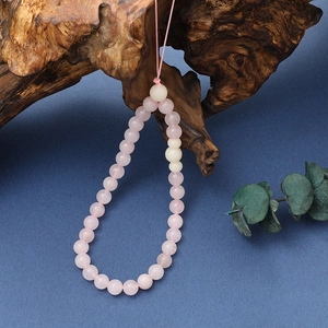 Detailed close-up of pink crystal beaded phone strap hanging on a natural wood root