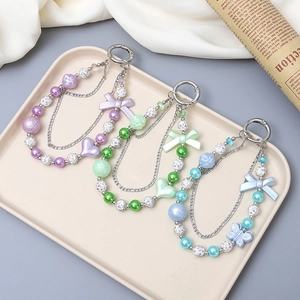Bijoux de téléphone perles cœur et nœud en couleurs macaron sur un plateau