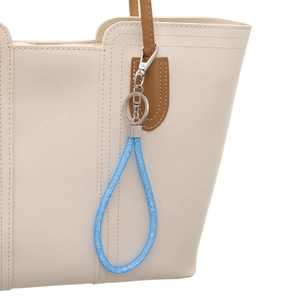 Blue rhinestone mesh lanyard keychain charm hanging on a beige leather handbag