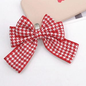 Close-up of red and white houndstooth bow hair clip with silver metal spring fastener
