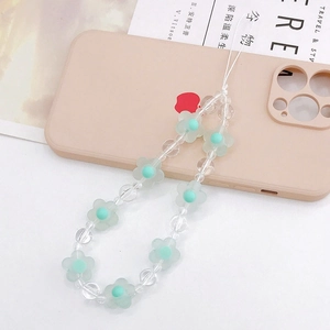 Frosted green acrylic flower beaded phone charm strap on a soft pink phone case