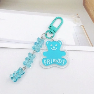 Détail du porte-clés ours bleu en acrylique avec texte Friends et attache mousqueton