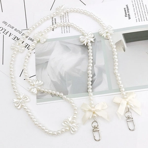 Elegant pearl phone chain with cream bows and silver clasp for a stylish crossbody look
