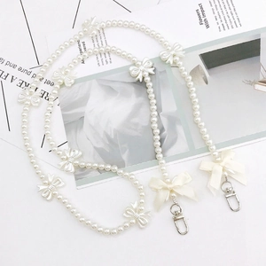 Elegant pearl phone strap with ribbon bows and silver clasps on a white background